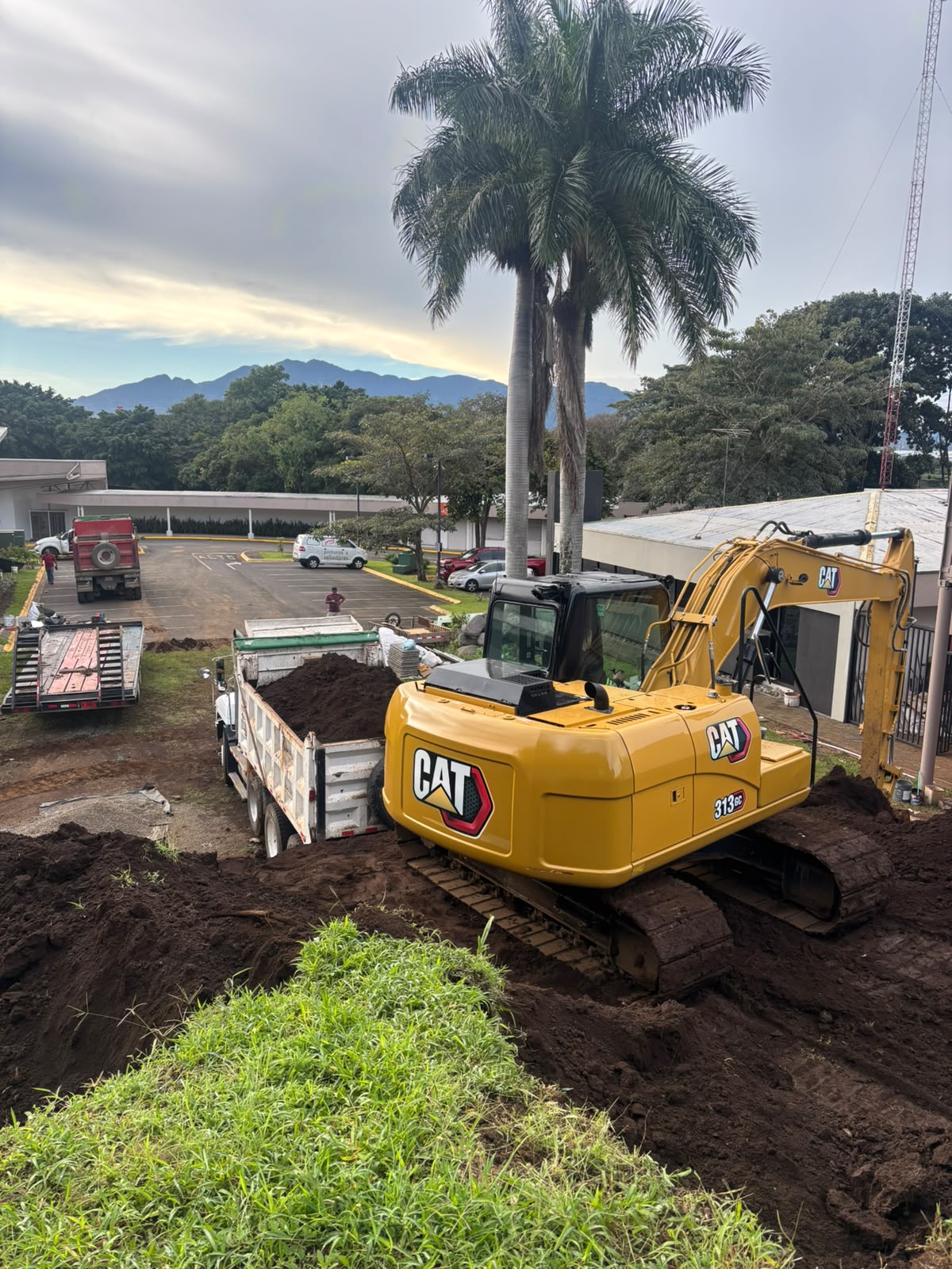 Excavadora CAT 313GC junto a vagoneta cargada de tierra en proyecto urbano