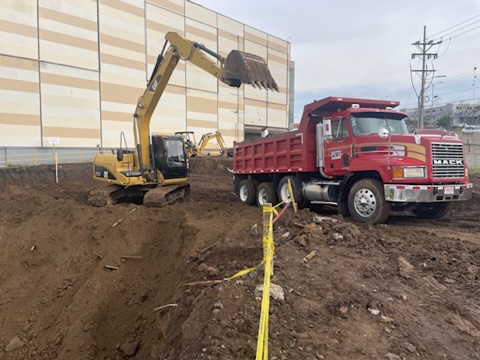 Excavadora SKY cargando una vagoneta roja Mack en obra de movimiento de tierra en Costa Rica