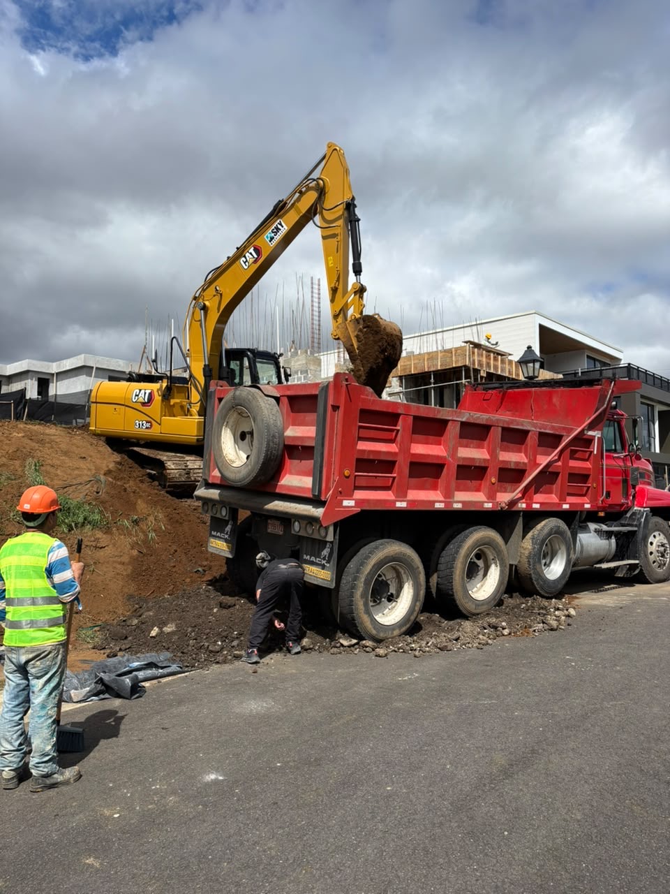Excavadora CAT cargando vagoneta roja Mack en proyecto residencial