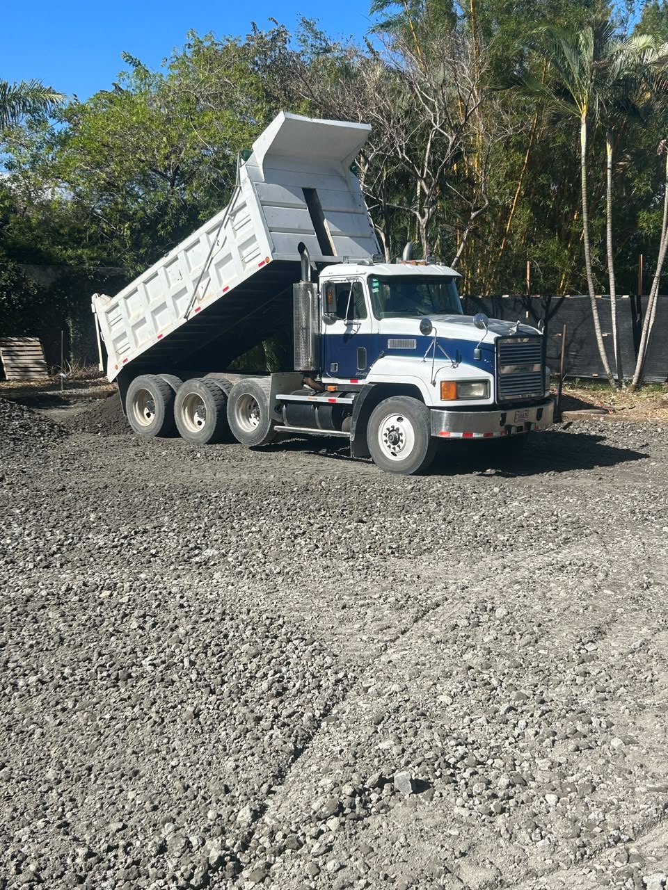 Vagoneta blanca descargando agregados en obra